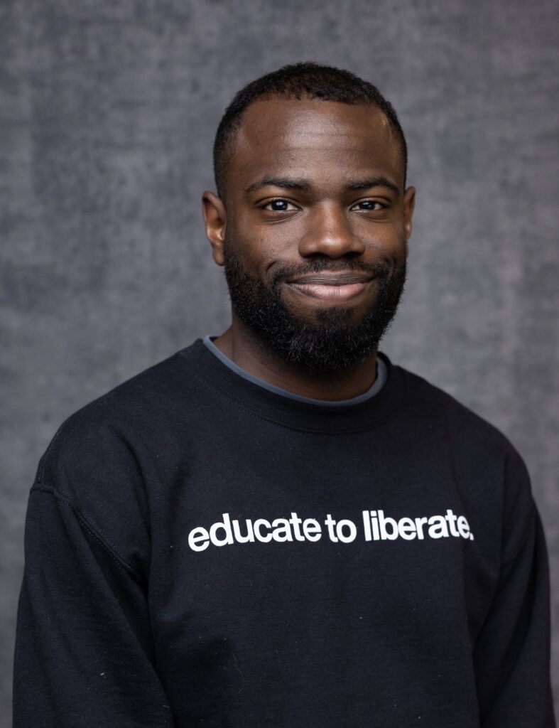 Malcom King, wearing a shirt that reads 'Educate to Liberate'