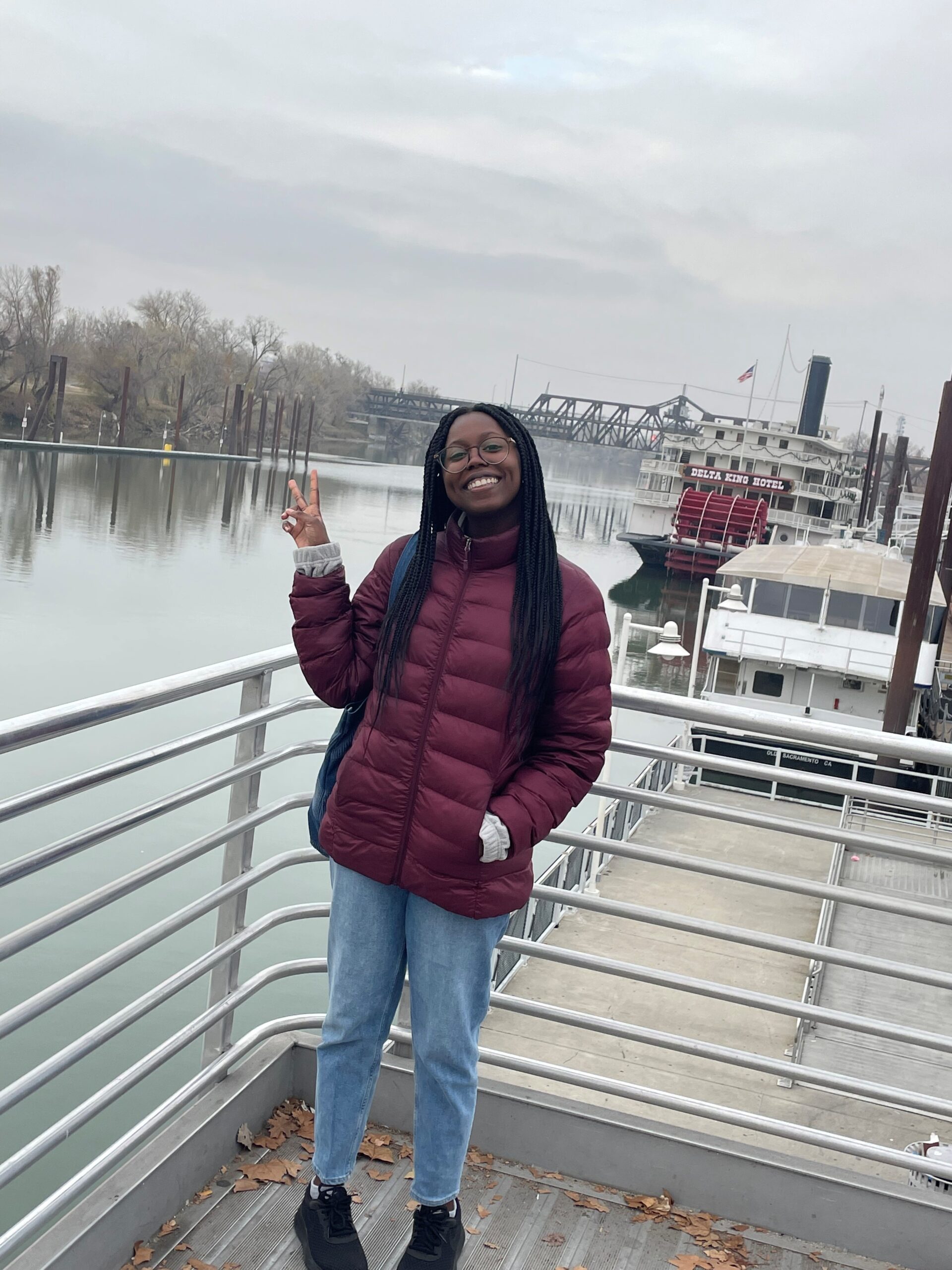 Nizan Howard stands on a dock overlooking a body of water smiling.