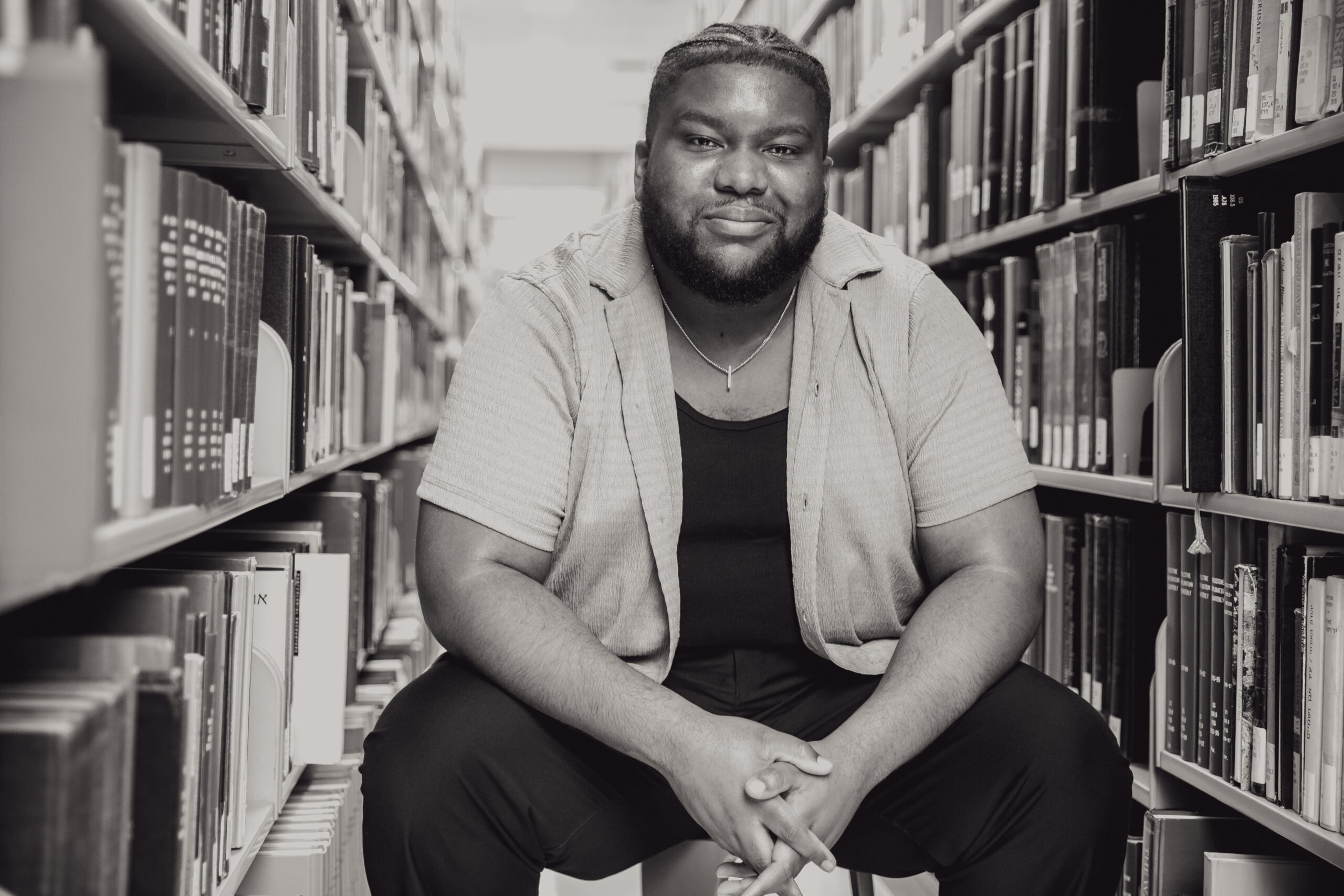 Black and white photo of Ramon Johnson sitting in a library.