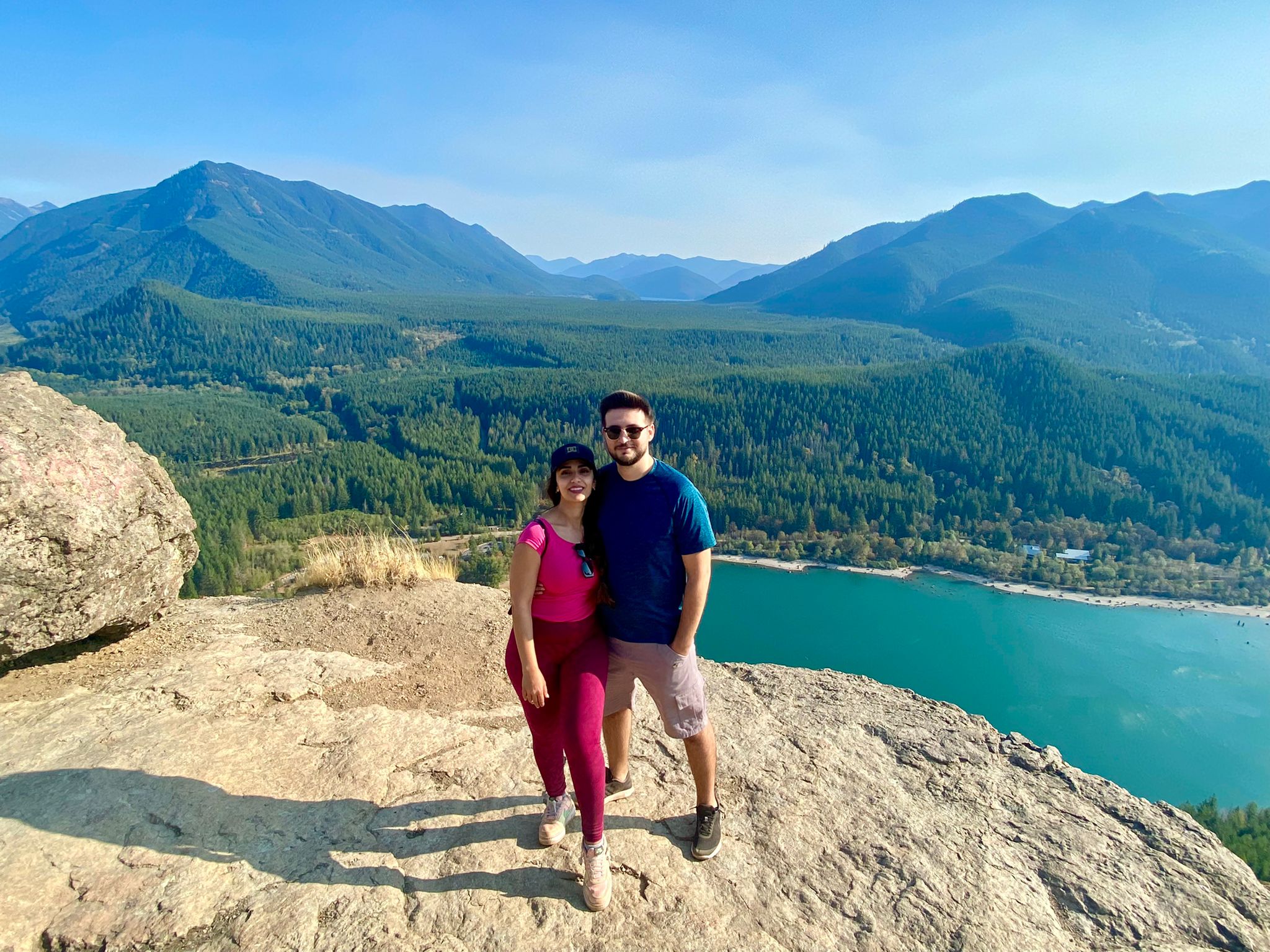 Lamis and her partner on top of a mountain with a crystal lake behind them.